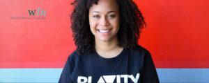 Morgan DeBaun smiles in front of a blue and red background, sporting a Blavity shirt.