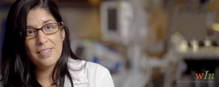 Dark-hairad woman in glasses and a white lab coat