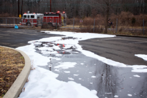 Image of foam in the street. In the background is a firetruck which ostensibly used the foam to put out a fire.