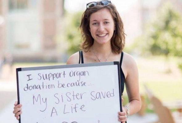 Sara Miller on WashU campus holding a whiteboard that says, "I support organ donation because my sister saved a life"