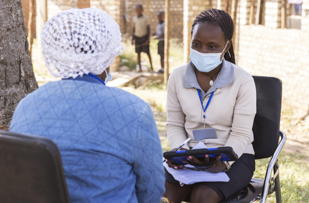 A Ugandan member of the ICHAD team (right) discusses the Suubi4Stronger Families study with a mother in the Masaka District. This study aims to stabilize families financially and teach parents ways to improve the behavioral health of children ages 10 to 14. (Photo: Thomas Malkowicz/Washington University)