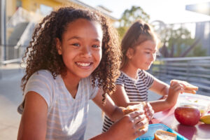 Two adolescent girls eating lunch outside