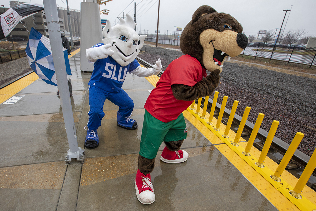 WashU Bear and SLU Billiken mascots on MetroLink platform