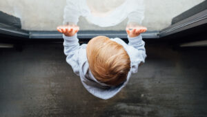 baby with hands on window