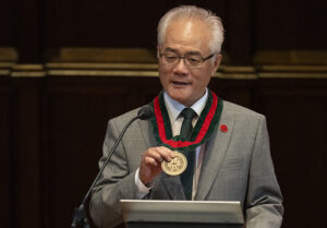 Feng Sheng Hu displaying his medallion during his installation as the inaugural Richard G. Engelsmann Dean of Arts & Sciences.