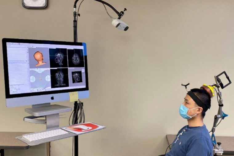 Graduate student Lu Xu wears a device designed by engineers that targets ultrasound waves to precise spots in the brain.