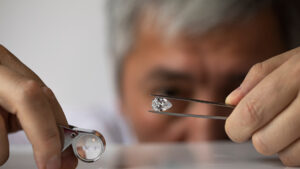 Jeweler looking at pear-shaped diamond.