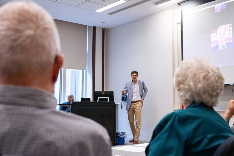 Joe MacDonald presenting in a classroom with Robert and Barbara Frick in the foreground.