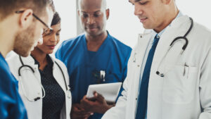 Team of multiracial doctors standing reading patient records on a ward round in a hospital