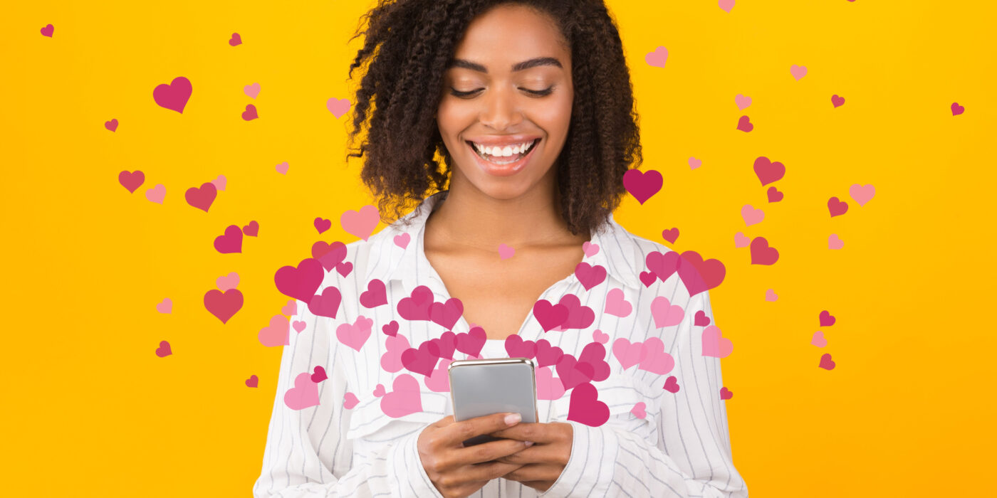 a woman looks at her phone while images of hearts flow around