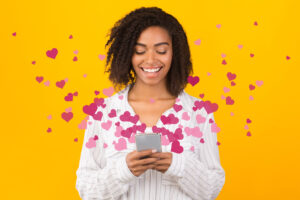 a woman looks at her phone while images of hearts flow around