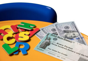 Children's letters of the alphabet, three $100 bills and a $300 U.S. Treasury check made out to Every Parent and marked Child Tax Credit are scattered on a table