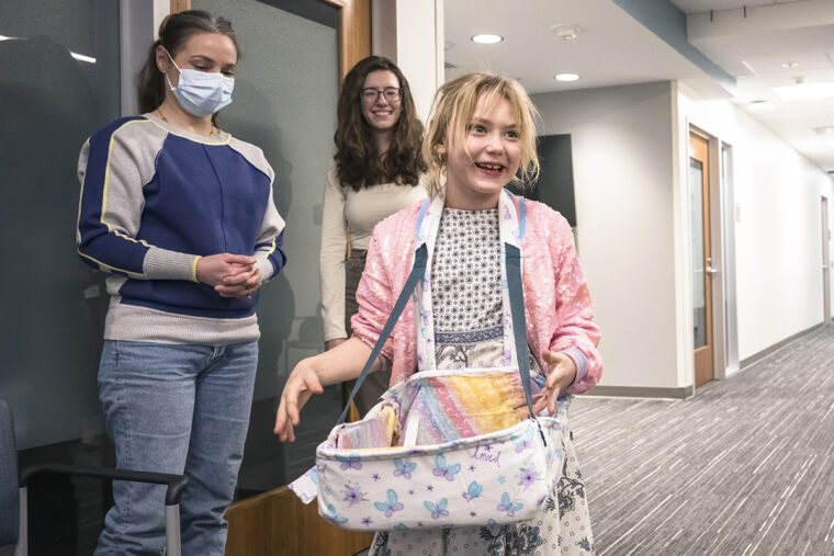 an occupational therapy patient with her mom and a student sporting her new device