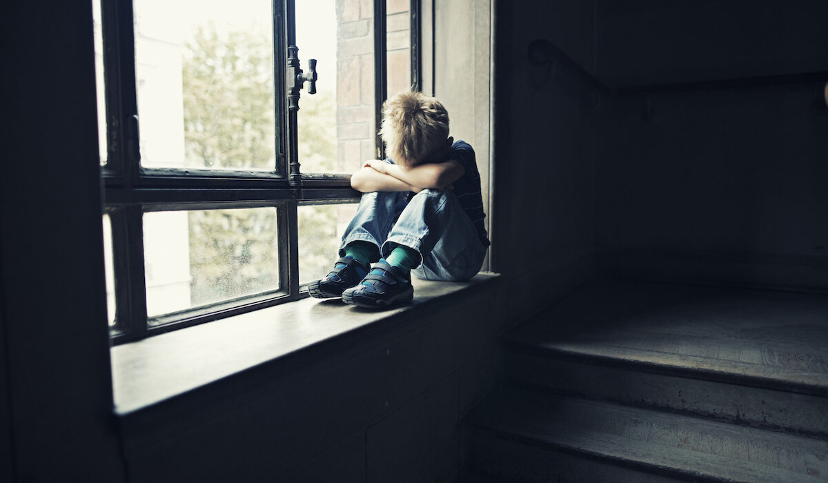 Depressed little boy in old staircase