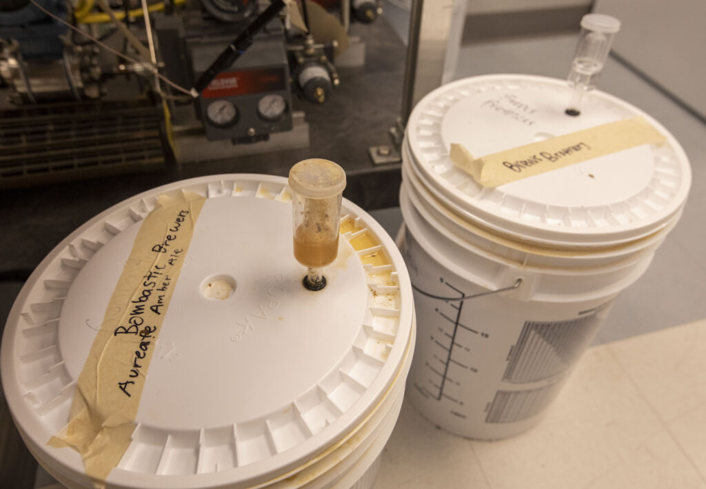 A plastic bucket labeled "Bombastic Brewers" from beer brewing class