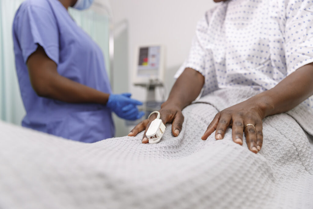 Close up shot of a black patient's hand with a finger pulse oximeter.