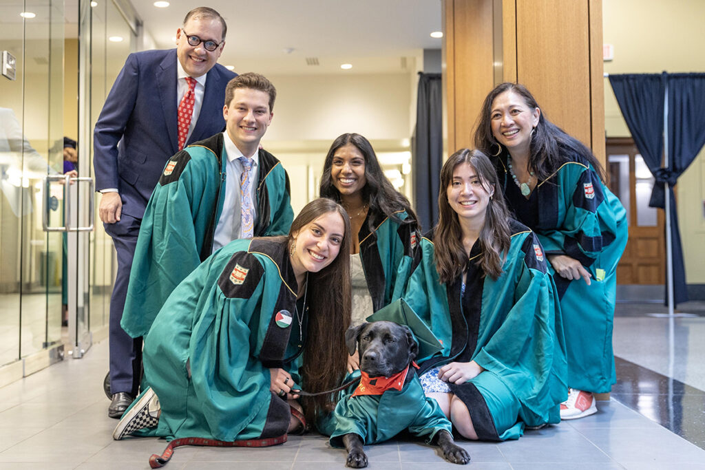 Chancellor Martin and Vice Chancellor Anna Gonzalez pose with graduates and WashU comfort dogs.