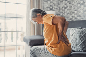 An elderly woman holds her lower back in pain