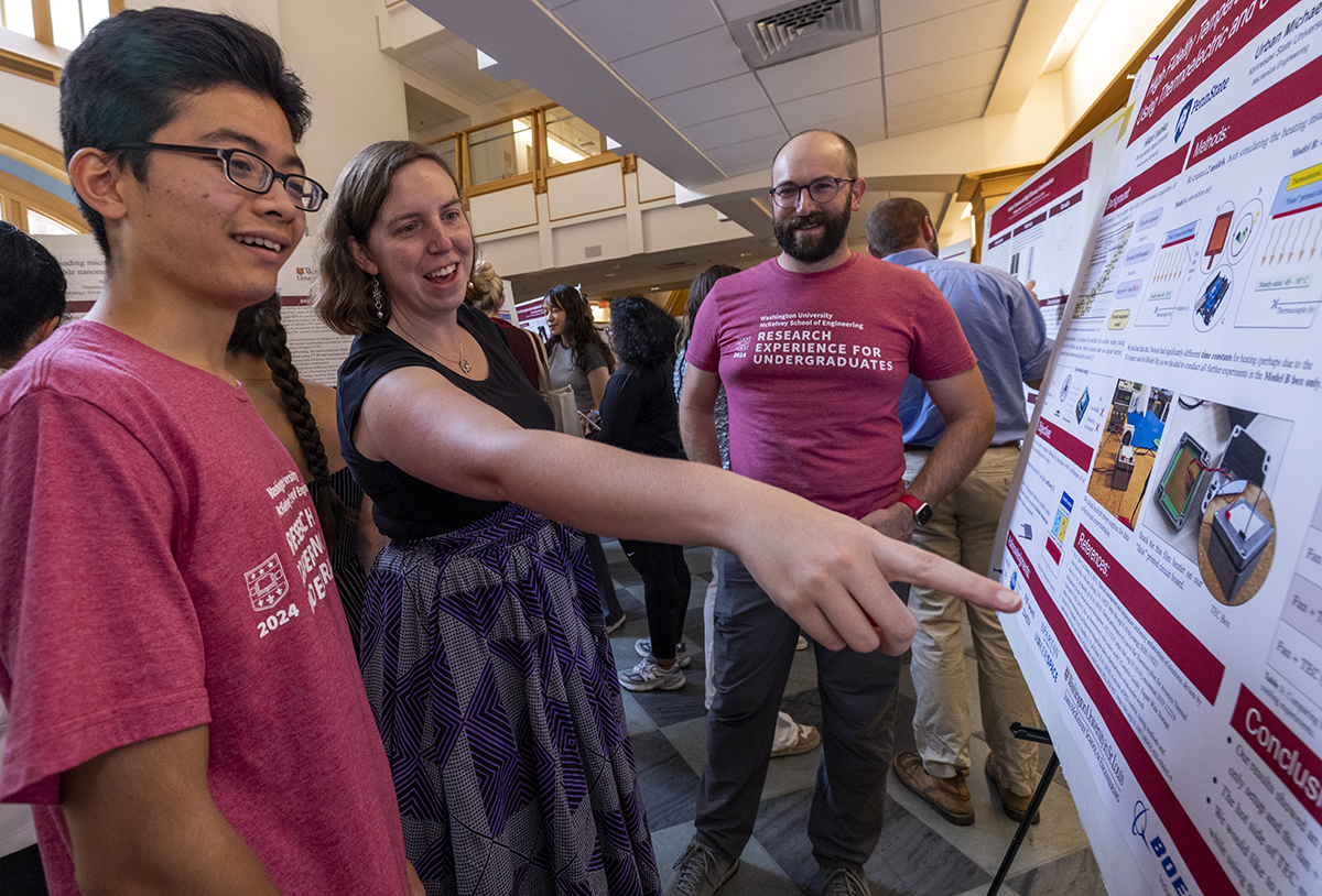 Janie Brennan speaks with students looking at a poster