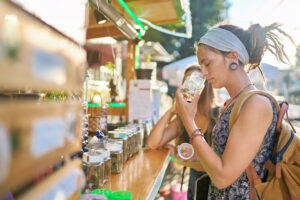 A white woman with dreads and a headband sniffs from a jar of cannabis
