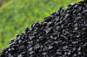 Pile of wet coal on green background.