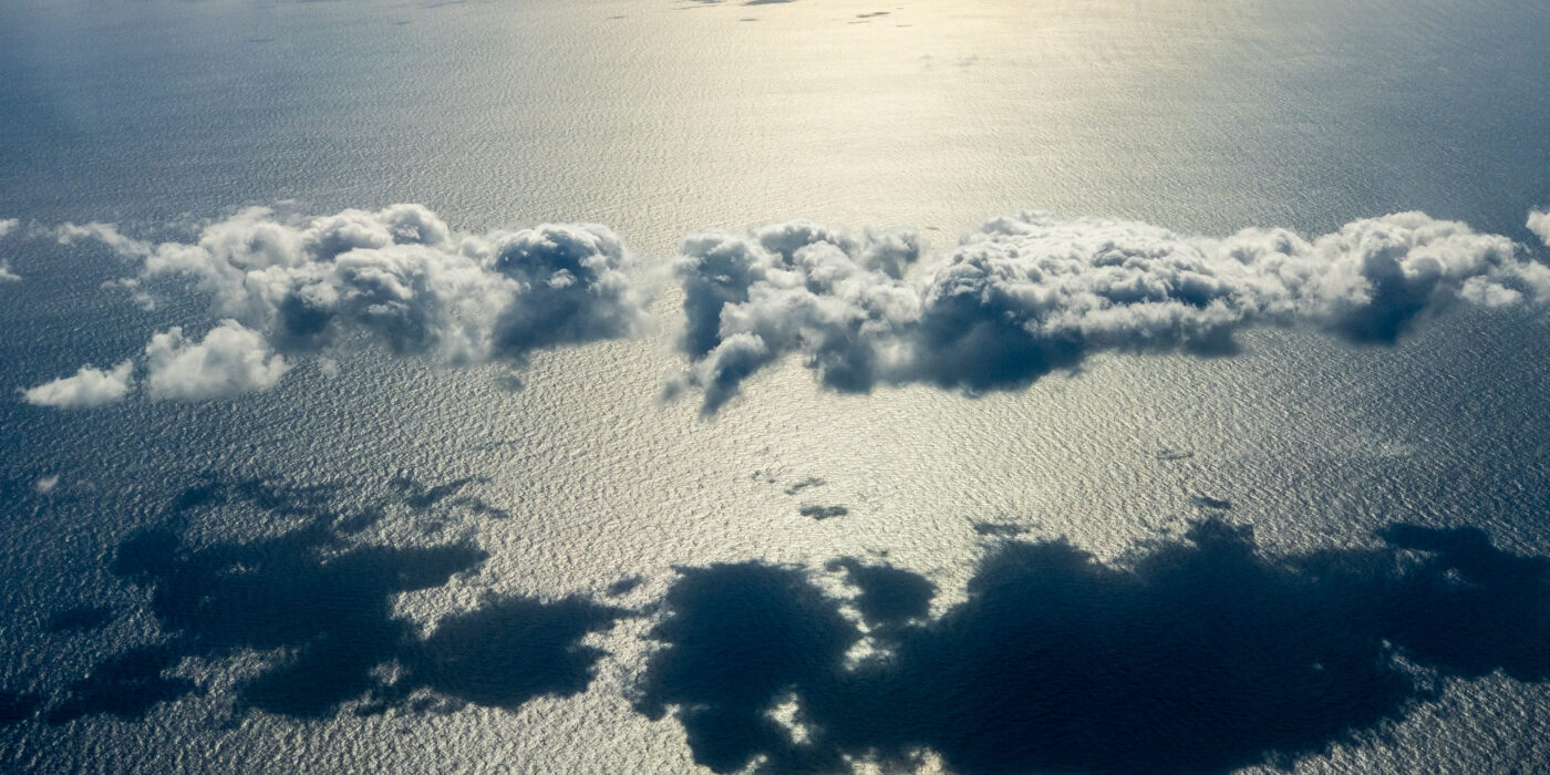 a view above the clouds as they cast shadow over ocean