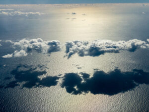 a view above the clouds as they cast shadow over ocean