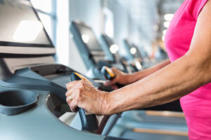 Close up of senior woman hands on the treadmill at gym. Elderly woman exercising on treadmill machine.