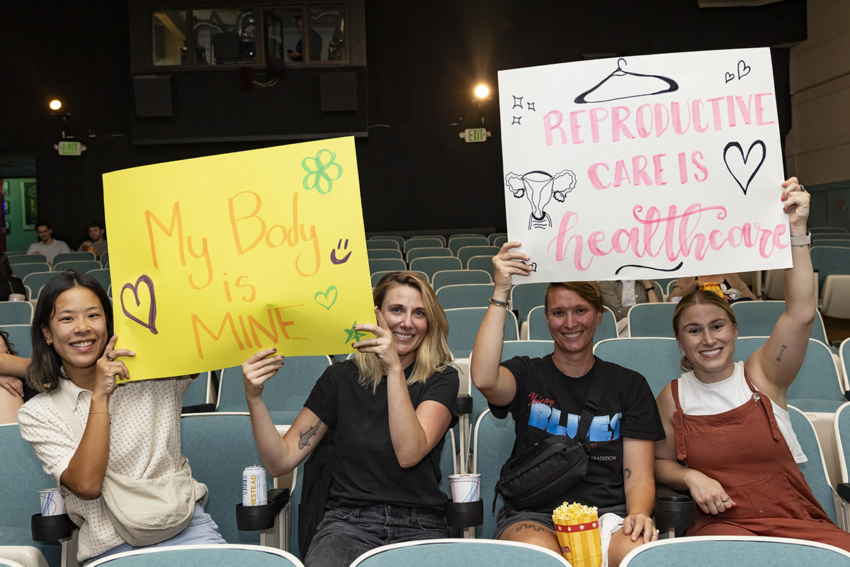 students at theatre holding posters