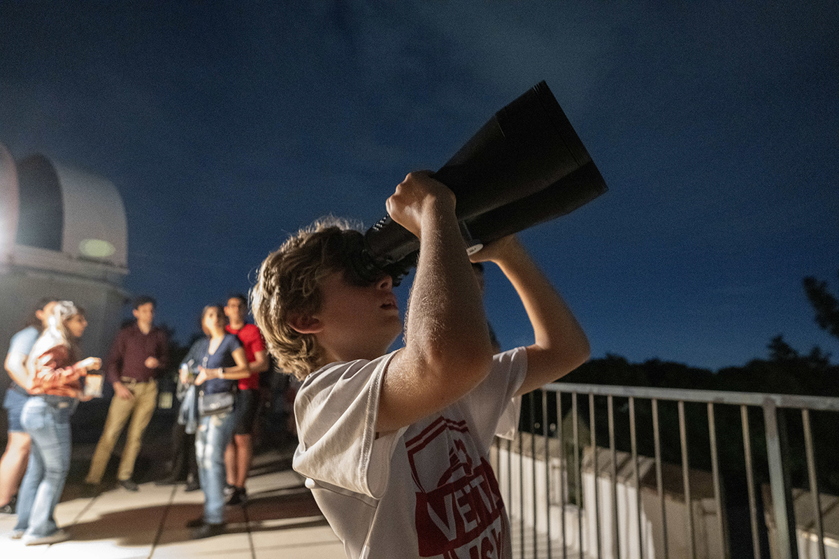 child uses binoculars to look at the moon