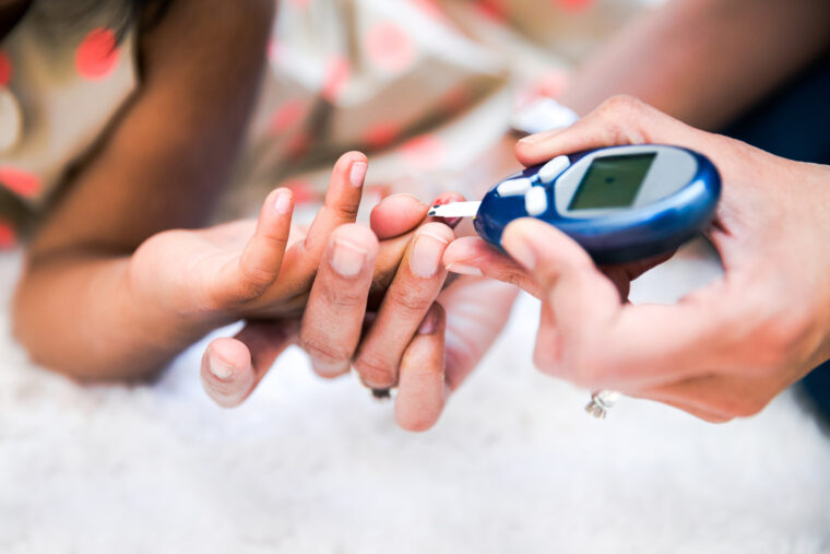 a photo of a child pricking their finger with a blood glucose test strip