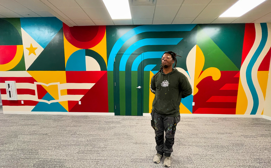 Artist stands in front of his mural