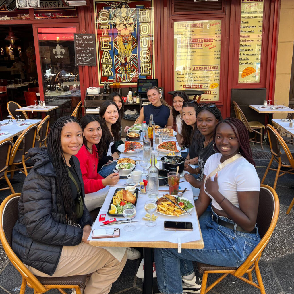 In addition to participating in the internship, Amsatou Mbacke (right, front), a senior, and fellow WashU students participated in French cultural experiences, including enjoying fine food. (Courtesy photo)