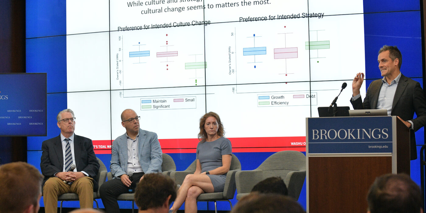 Seated panel of Bart Hamilton, Mike Mazzeo and Lynn Gorguze with Peter Boumgarden speaking at the commission presentation at the Brookings Institution.