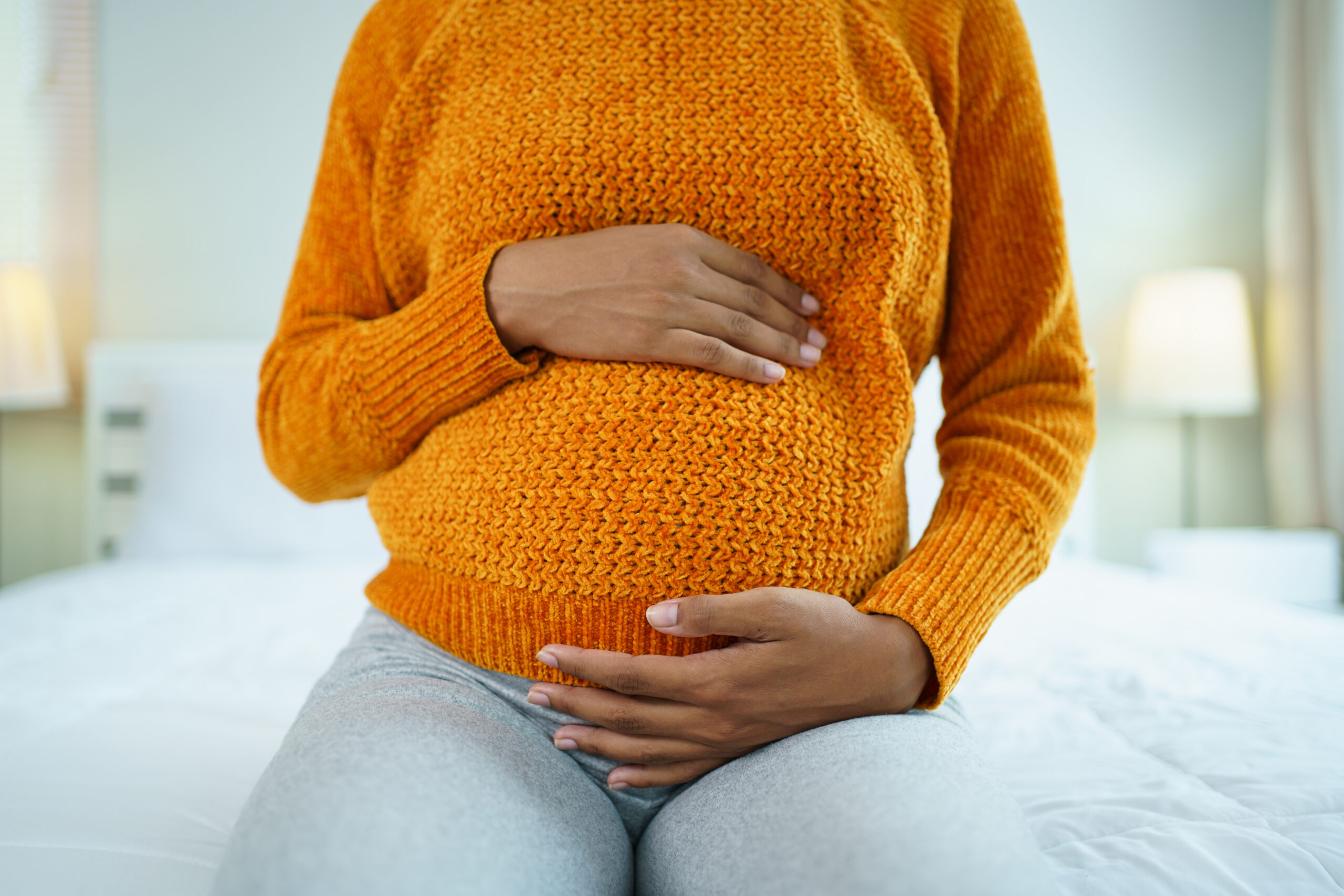 A pregnant woman cradles her stomach.