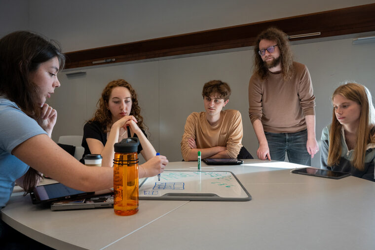 students work on a whiteboard on a table in class