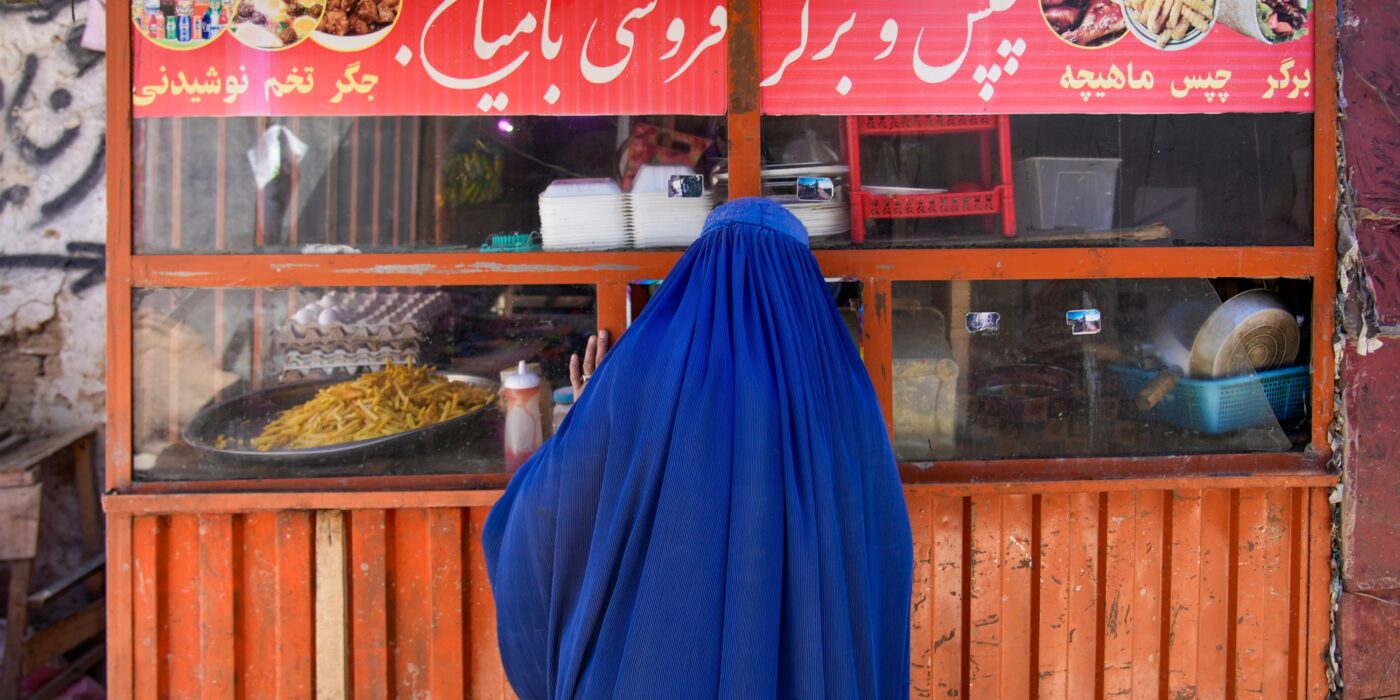 a woman in a burqa tries to get food