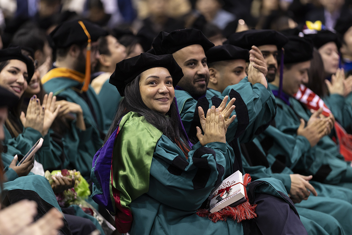 Graduates clap while sitting in audience