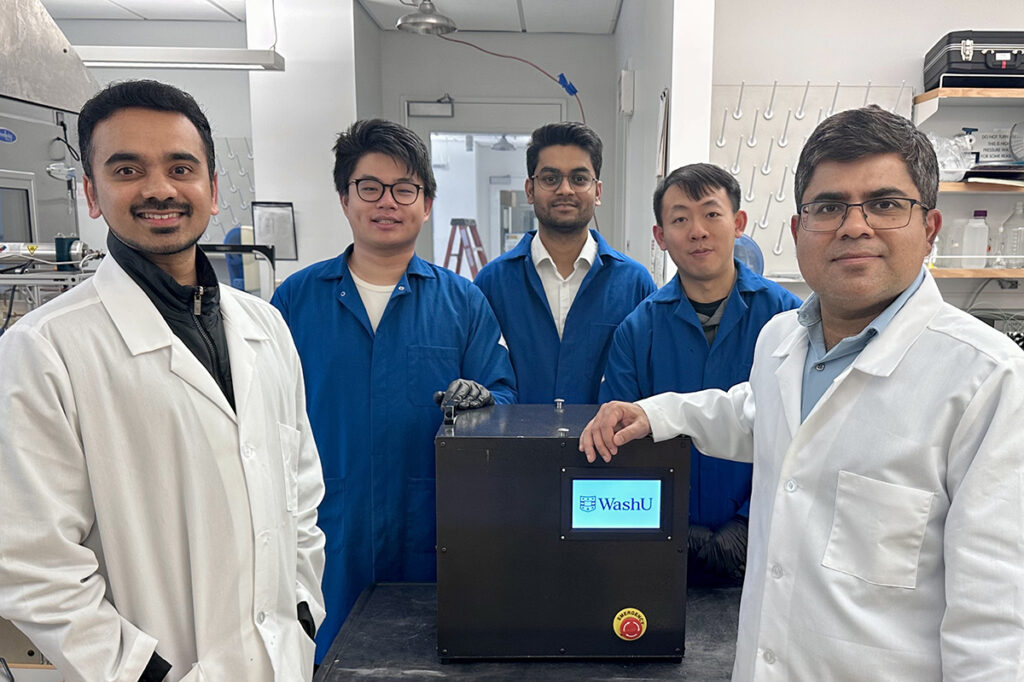 A team of researchers posing next to a printer sized device