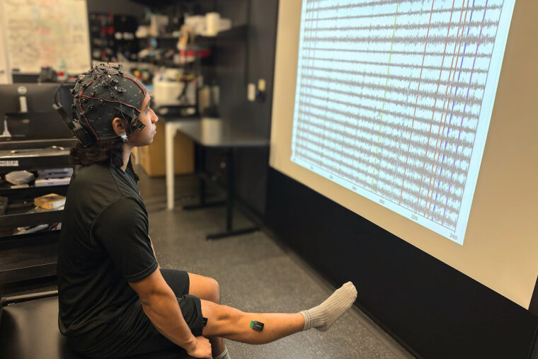 a person holding their leg up while looking at a screen and wearing a device on their head
