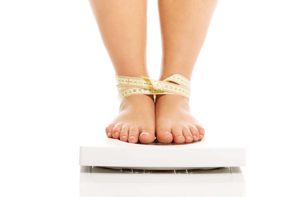 feet on a scale all tangled in measuring tape