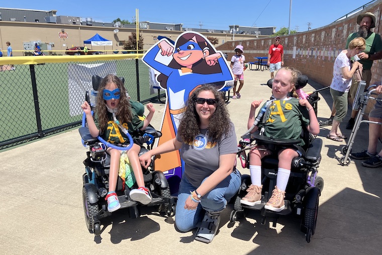 Lisa Kollins (center), AB '96, attends a game of the Miracle League of Lake County, an inclusive baseball league in Eastlake, Ohio. League players "Queen Adilynne" (right) and "Clare Bear" are participants in The Superhero Project, the nonprofit Kollins founded in 2020. (Courtesy photo)
