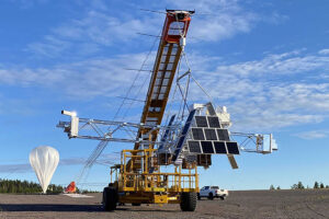 a balloon and large crane lifting a satelite
