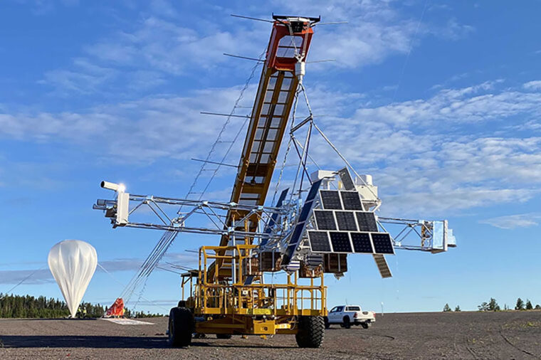 a balloon and large crane lifting a satelite
