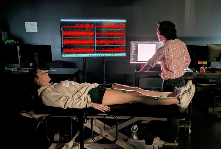a person lying down while another looks at a computer