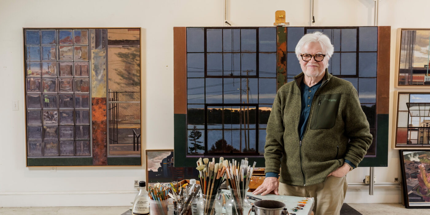 The artist John Moore in his Maine studio. The artwork behind him, at left, is “Crossing Guard” (oil on canvas, 2022); and “Dawning” (oil on canvas, 2026).